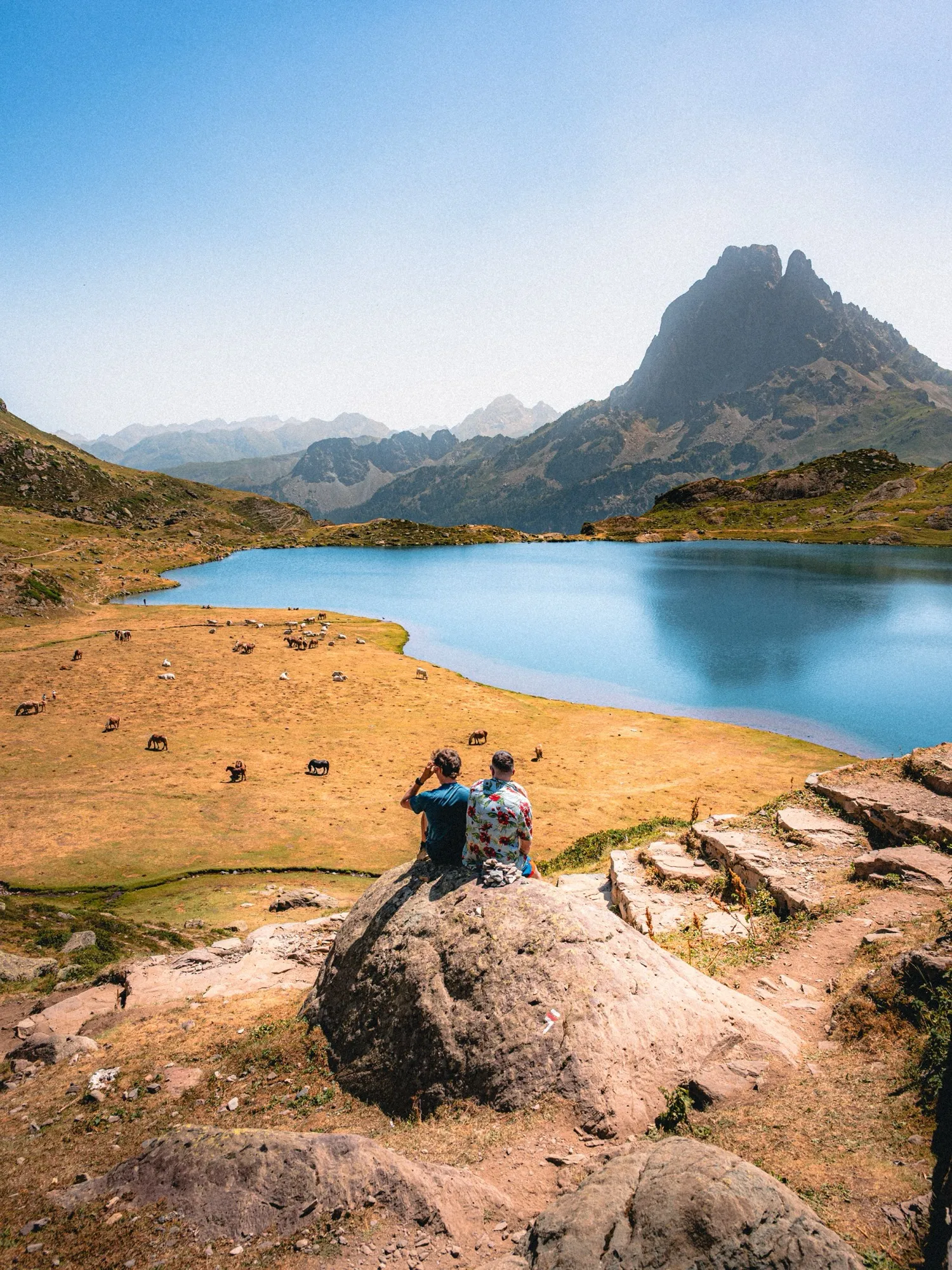 Deux randonneurs en pause au bord d'un lac face au Pic du Midi d'Ossau