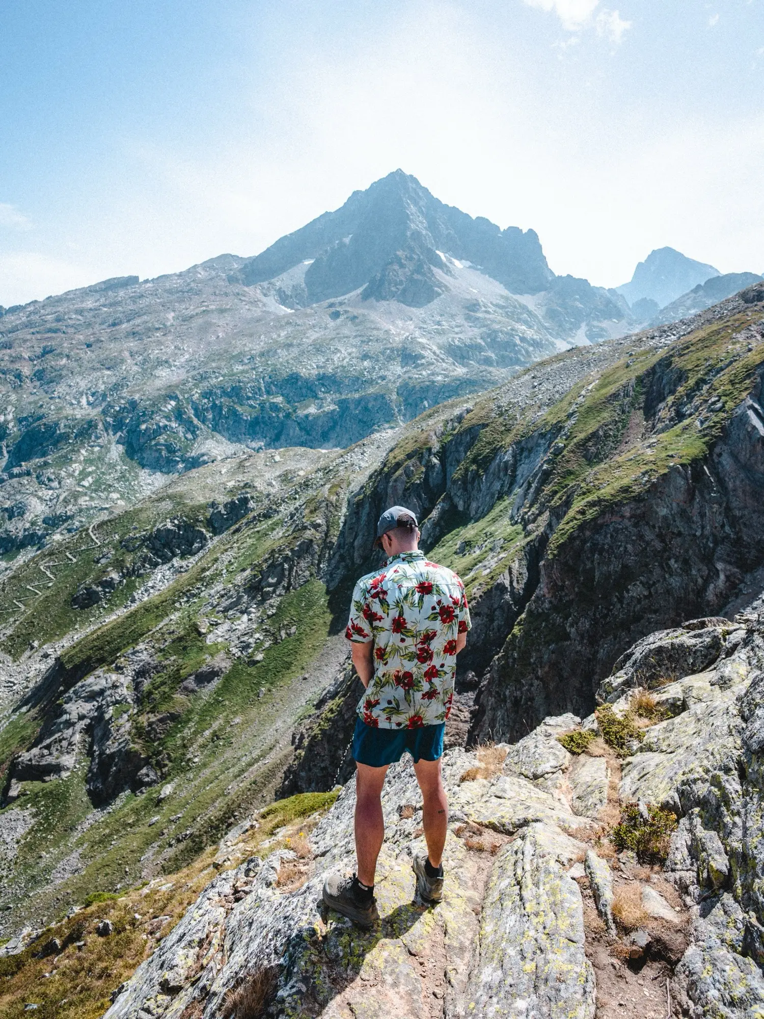 A hiker standing on a rock, with mountains behind him