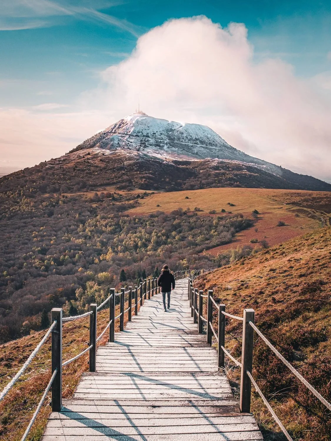 Un sentier en caillebotis qui monte vers un sommet enneigé